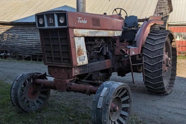 1960s IH 1566 Turbo tractor back view with rust, belt-style grille, single exhaust, large rear tires.