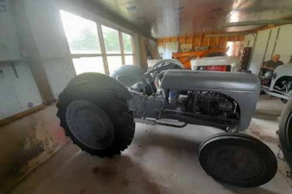 Restored 1939 Ford 9N tractor with open engine and large rear tires in a workshop.