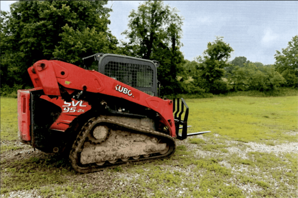 2016 Kubota SVL95-2 compact track loader with enclosed cab and rubber tracks on grassy terrain.