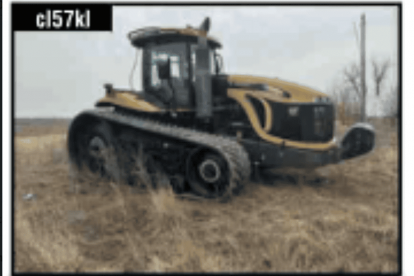John Deere 8R tractor with tracks and enclosed cab in a field.