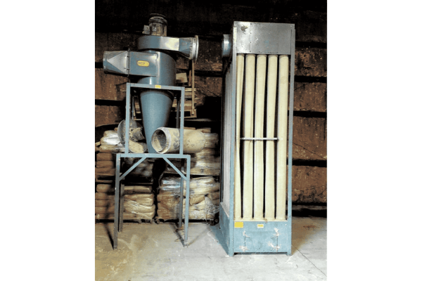 Industrial dust collector system with large filter unit and cyclone separator, used for air purification in manufacturing fac.