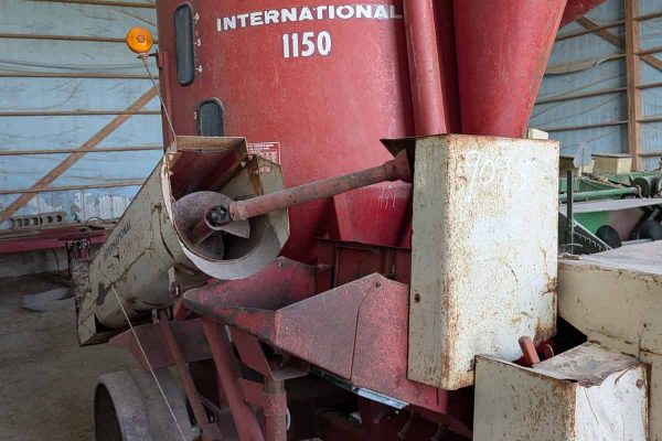 International 1150 grain auger with red hopper and conveyor in storage barn.