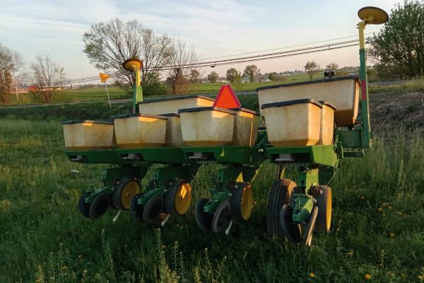 Vintage green and yellow agricultural planter with seed hoppers, outdoor setting, no visible year or model.