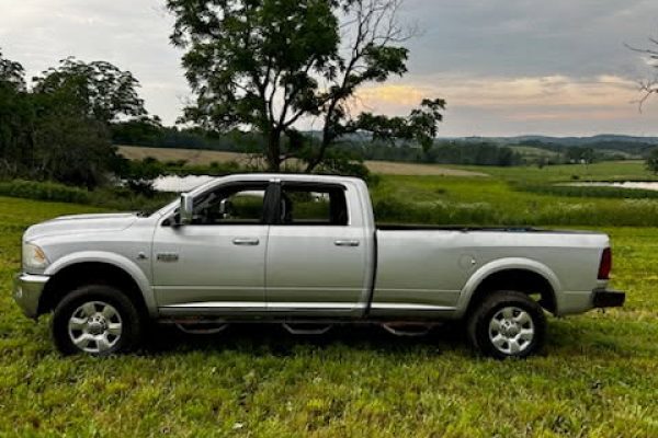 Silver 2021 Ram 2500 pickup truck with extended cab and long bed on grassy field.