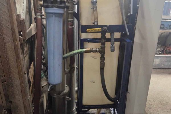 Industrial water filtration system with pipes and filters in a workshop setting.