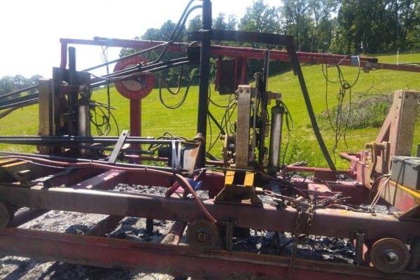 Heavy-duty industrial sawmill equipment with hydraulic components and conveyor system.