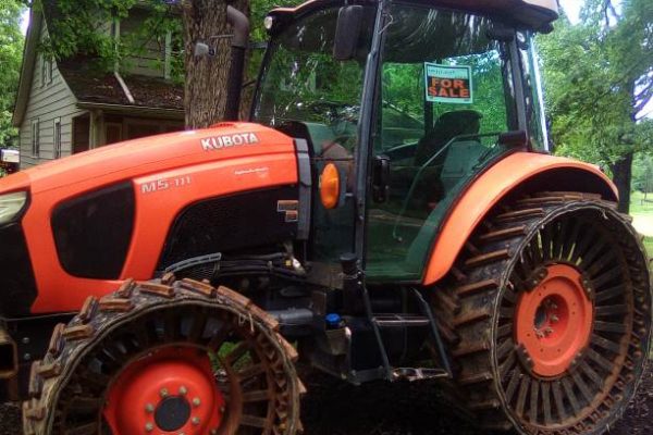 2018 Kubota M5-111 tractor with rubber tracks and enclosed cab in outdoor setting.