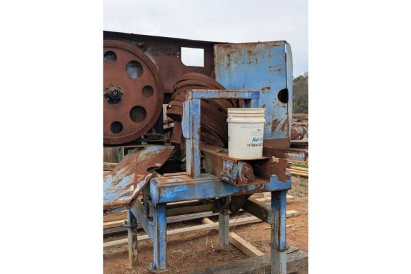 Old blue and rusted industrial machine with a white bucket, no visible brand or model, outdoors on a dirt surface.