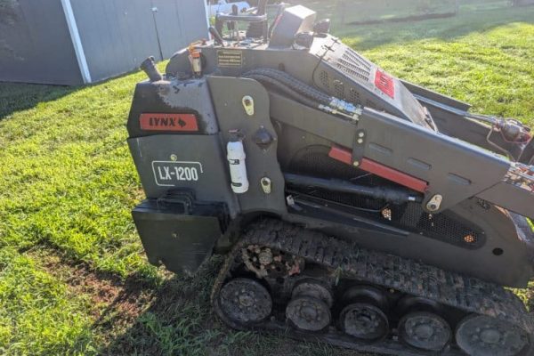 2023 Lynx LX-1200 compact tracked loader with cab and rubber tracks on grassy area.