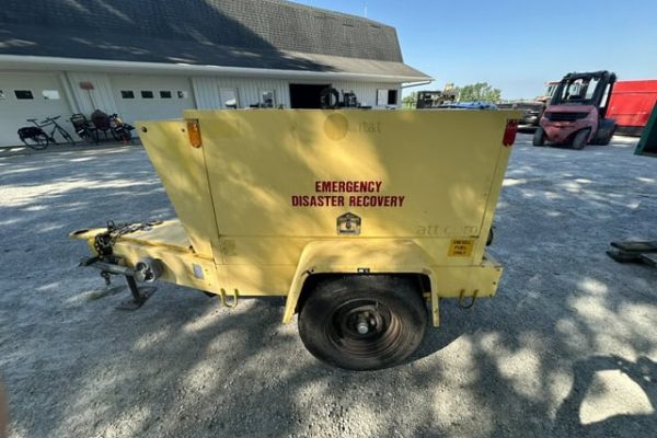 Yellow emergency disaster recovery trailer with single axle and black wheel, parked on gravel.