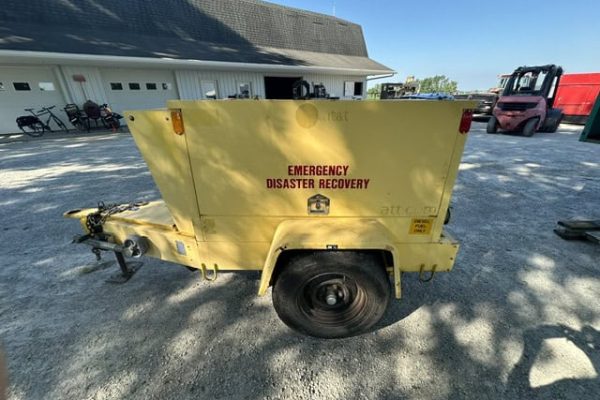 Yellow emergency disaster recovery trailer with single axle and black wheel, parked on gravel.