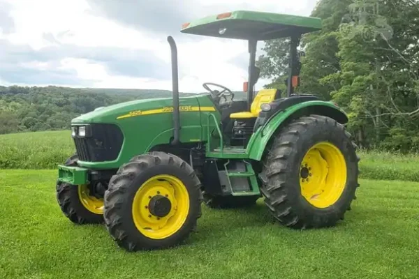 2007 John Deere 5425 tractor with cab and large rear tires on grassy field.