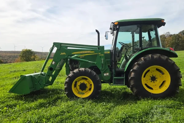 2010 John Deere 5101E compact tractor with front loader and enclosed cab on grassy field.