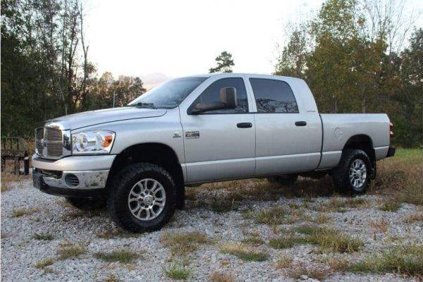 Dodge Ram 2500 4x4 pickup truck parked outdoors on gravel with trees in the background.