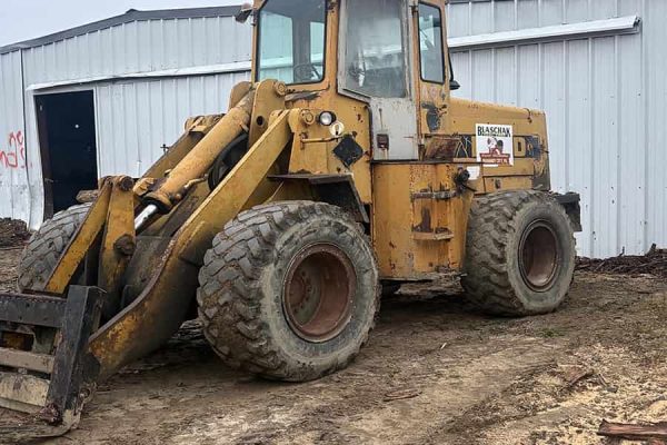 Yellow Ford A64 wheel loader with enclosed cab and large tires on dirt ground.